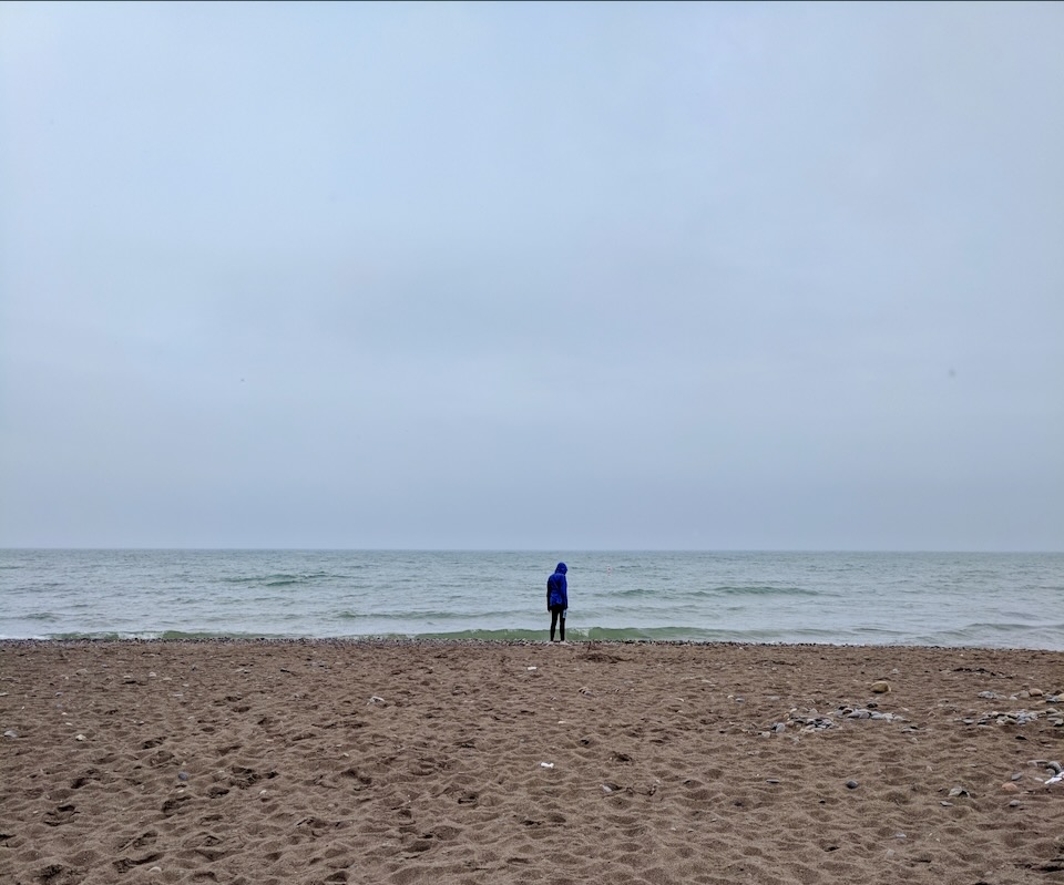 Lone person on the beach by a great lake on a cloudy day
